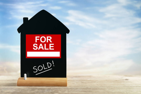 木質背景上的銀色鑰匙與房屋頂部視圖符號 房地產廣告的視覺語言